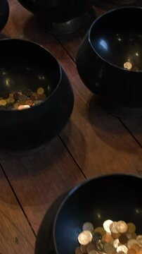 Vertical video. Rows of traditional Thai alms bowls arranged together on display inside the temple