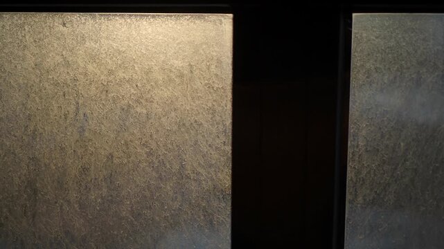 Close-up of dust motes dancing in sunlight passing through a dirty window pane