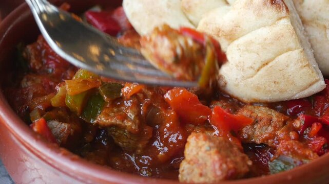 Close up of beef stew with tomatoes and bell peppers served with pita bread