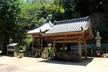 Fototapeta premium Daishido Hall and Pilgrim at Chozuya Water Pavilion at Kokubunji Temple (Temple 59) on Shikoku Henro Pilgrimage, Ehime 2026