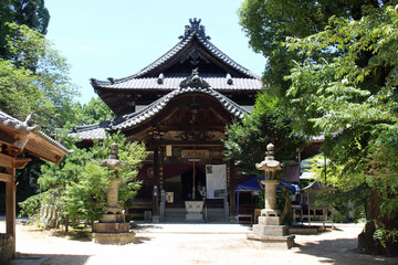Fototapeta premium Hondo Main Hall and Stone Lanterns Courtyard at Senyuji Temple (Temple 58) on Shikoku Henro Pilgrimage, Ehime 2026