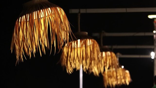 Traditional woven thatch lampshades glowing with warm light at night at Srinakarin Dam in Kanchanaburi Thailand