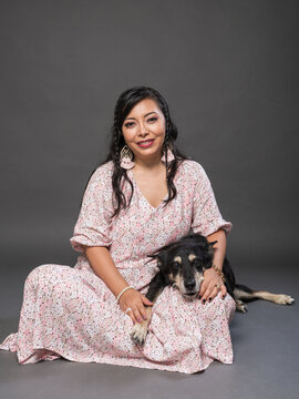 Woman Posing with Dog in Floral Dress Against Dark Studio Background