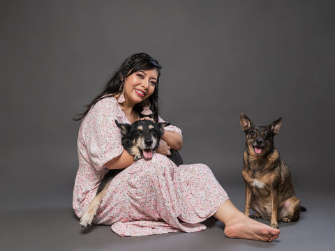 Woman Sitting with Two Dogs in a Studio on Gray Background