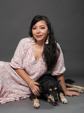 Woman Posing with Dog in Floral Dress Against Dark Studio Background