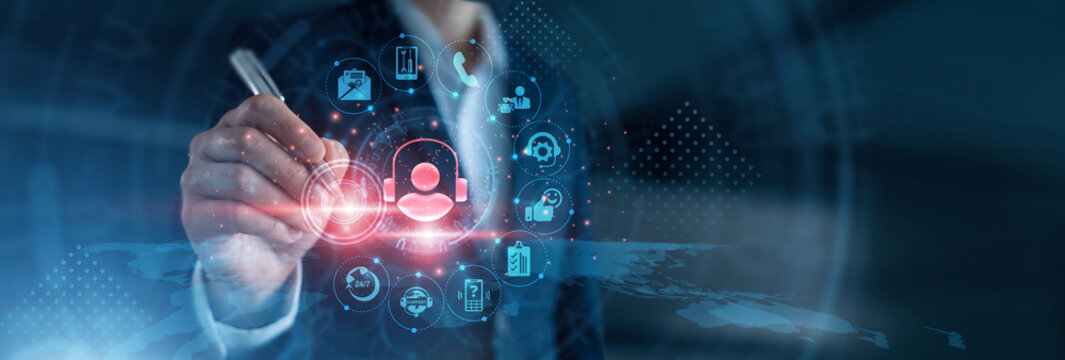 Client assistance. Support agent wearing headset using dual monitor displays tracking service tickets, response times, and communication logs on live network portal. Helpdesk operations.