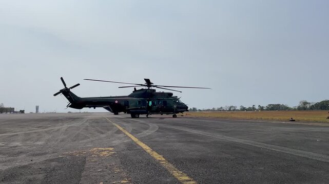 Indonesia - 02 September 2026: View of a military helicopter parked on the tarmac at an airfield under a clear sky.