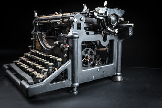 Vintage typewriter machine on a dark low key background. Close up of antique mechanical writing tool, retro journalism equipment, and nostalgic author conceptual background.