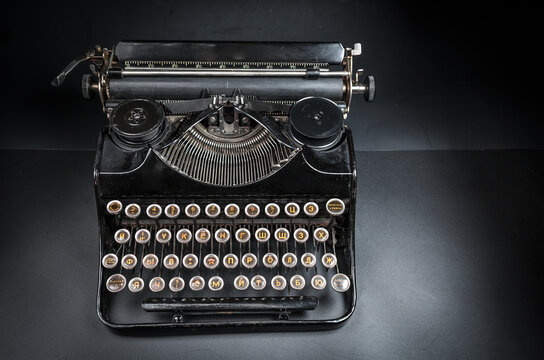 Vintage typewriter machine on a dark low key background. Close up of antique mechanical writing tool, retro journalism equipment, and nostalgic author conceptual background.
