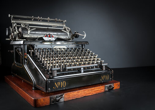 Vintage typewriter machine on a dark low key background. Close up of antique mechanical writing tool, retro journalism equipment, and nostalgic author conceptual background.