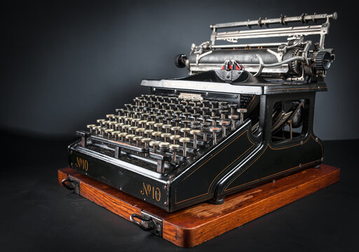 Vintage typewriter machine on a dark low key background. Close up of antique mechanical writing tool, retro journalism equipment, and nostalgic author conceptual background.