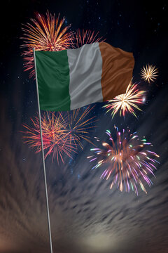 Waving National flag of Ireland and holiday fireworks in night sky
