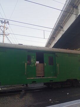 Green Freight Train Boxcar Under Highway Overpass in Urban Railway Yard