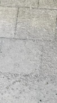 Heavy rain falls on the sidewalk 