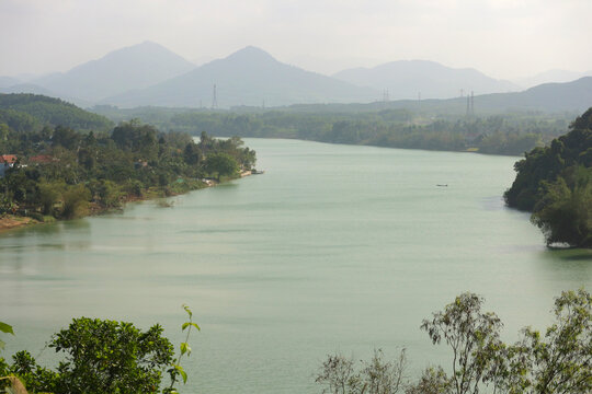 Scenic panoramic view of Perfume River flowing through tropical valley with misty mountains background in Hue, Vietnam