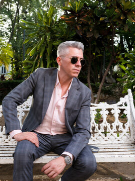 Elegant Man in Suit and Sunglasses Sitting on a Park Bench
