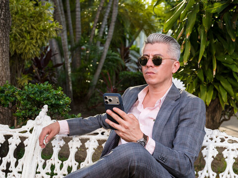 Elegant Man in Suit Using a Cell Phone on a Park Bench