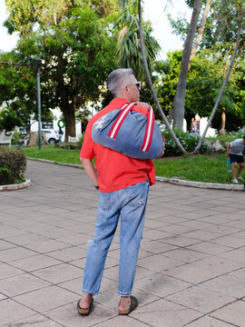 Man with White Sunglasses and Backpack Walking Through a Public Park
