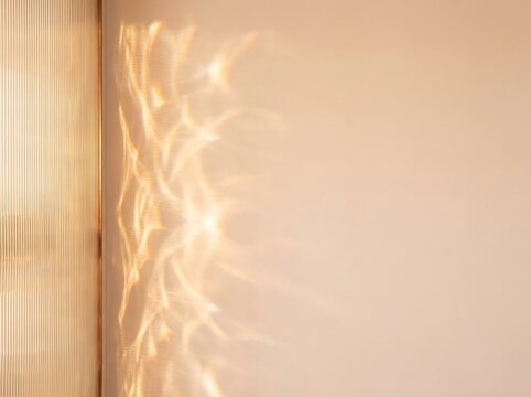 Warm golden sunlight caustic reflections through ribbed glass window onto beige plaster wall
