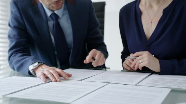Business people hands discussing contract terms and analyzing paperwork, reviewing legal documents during a corporate meeting in a modern office, planning strategy