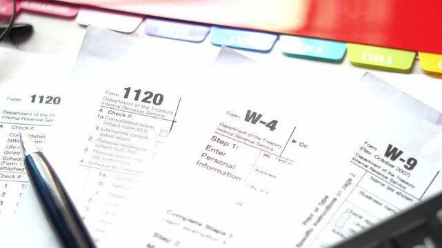 Close up motion footage showing various tax forms with pen and calculator on desk representing finance and accounting