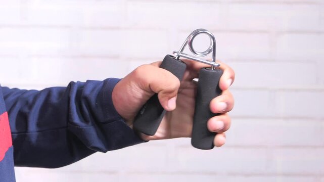 Close up hand squeezing hand grip strengthener for forearm workout