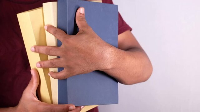 Man holding stack of colorful books close up view on white background in slow motion