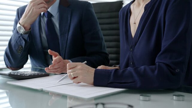 Business colleagues working together at a desk. Reviewing financial documents and utilizing a calculator for tax calculations or budget analysis