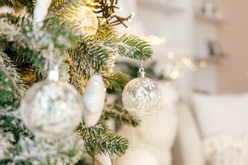 Naklejka premium Christmas tree decoration with glass ornaments and warm lights in a cozy living room