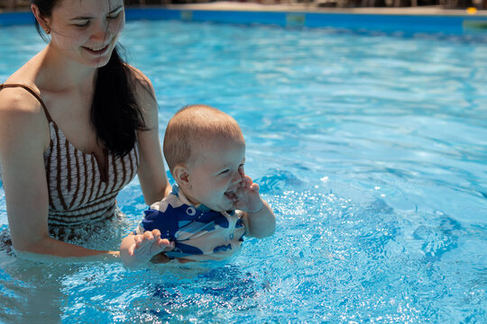 Mother and baby enjoying a refreshing swim together in a bright blue swimming pool