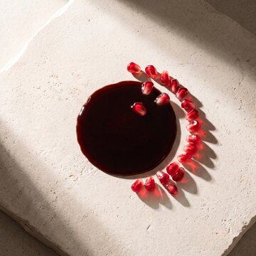 Pomegranate molasses circle with ruby arils on stone