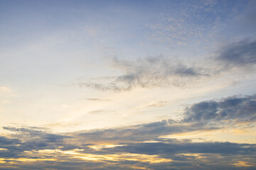 Fototapeta premium Soft morning sky with gentle clouds and golden light,A wide view of a peaceful blue sky illuminated by soft golden sunlight, filled with gentle wispy clouds during early morning sunrise or evening.