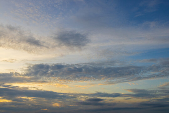 Soft morning sky with gentle clouds and golden light,A wide view of a peaceful blue sky illuminated by soft golden sunlight, filled with gentle wispy clouds during early morning sunrise or evening.