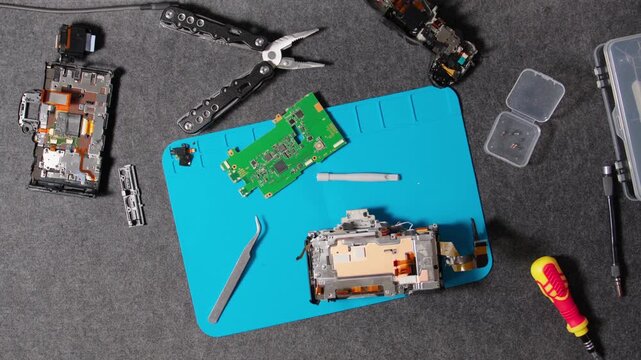 Disassembled camera components laid out on workstation mat for repair.