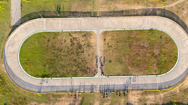 Aerial view of an oval cycling track with a grassy infield and people standing along the concrete perimeter in Bantul, Special Region of Yogyakarta, Indonesia.