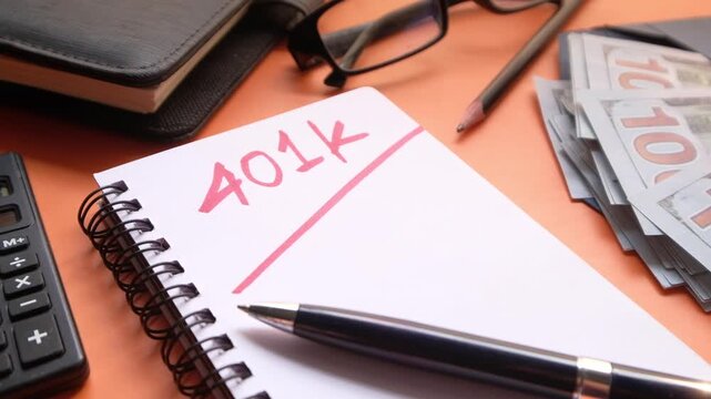A 401k retirement plan concept featuring a calculator, cash money, and a notebook with pen on an orange table