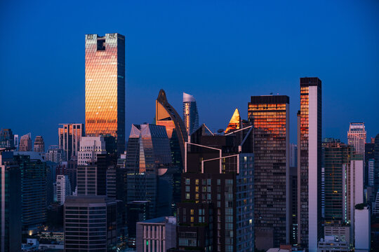 Aerial view of the One City Centre skyscraper reflecting golden sunset light amidst the modern skyline of Bangkok, Krung Thep Maha Nakhon, Thailand.