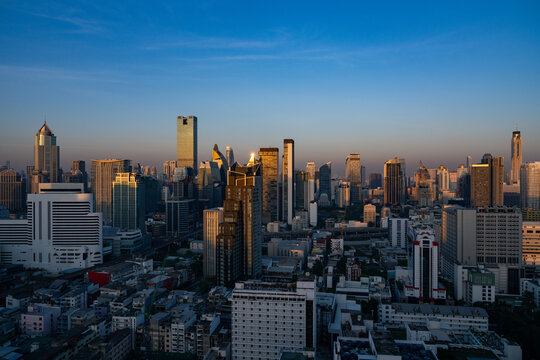 Aerial view of the Bangkok skyline at sunset with modern skyscrapers, glass facades, and urban density in Bangkok, Bangkok, Thailand.
