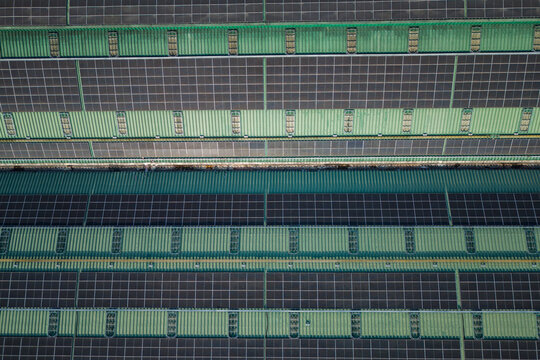 Aerial view of rows of solar panels installed on a green metal roof of an industrial building in Salatiga, Central Java, Indonesia.