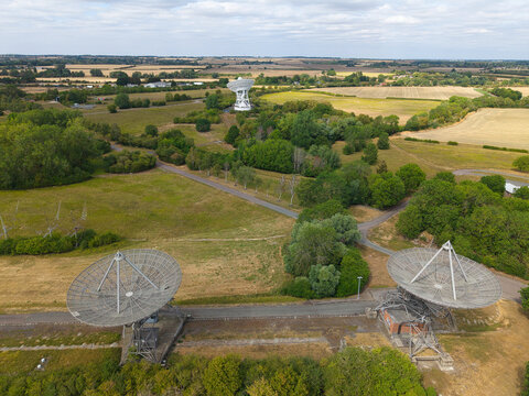 Aerial view of Mullard Radio Astronomy Observatory with large radio telescope dishes situated in a rural landscape with fields and trees in Harlton, England, United Kingdom.