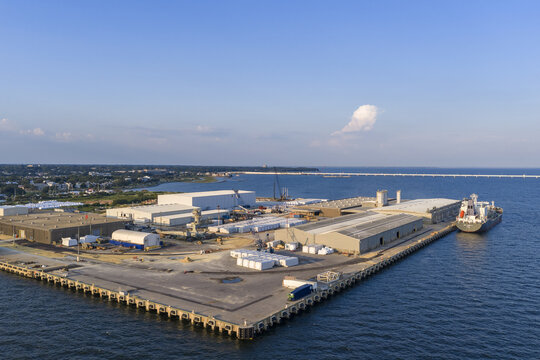 Aerial view of CEMEX Pensacola Cement Import Terminal with industrial warehouses, storage facilities, and a cargo ship docked at the pier in Pensacola, Florida, United States.