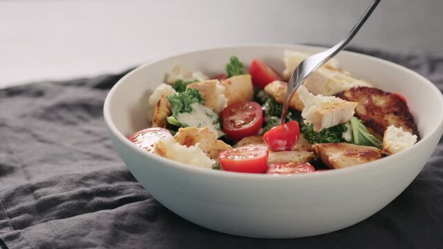 Slow motion man tastes caesar salad with kale and turkey in white bowl