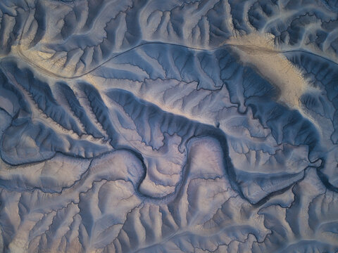 Aerial view of the intricate erosion patterns and badlands surrounding Factory Butte, featuring deep ridges and valleys in the desert landscape of Wayne County, Utah, United States.