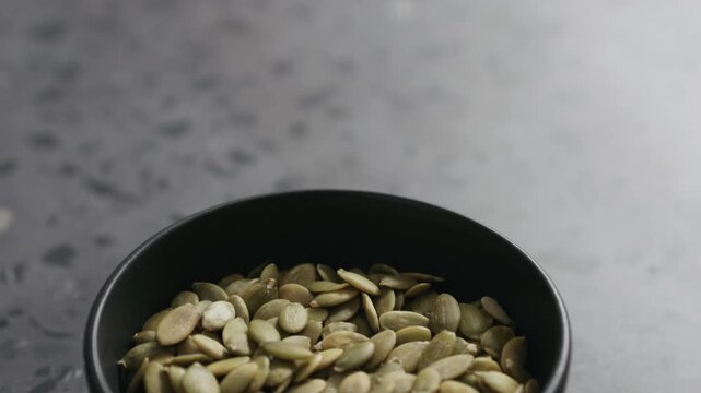 Slow motion handheld shot of pumpkin in black bowl on terrazzo countertop