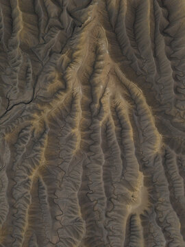 Aerial view of the intricate, eroded badlands and ridges of Factory Butte, showcasing the dramatic textures and patterns of the desert landscape in Wayne County, Utah, United States.