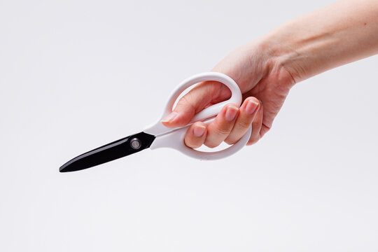 Woman hand holding white scissors isolated on white background