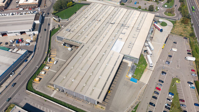 Aerial view of the Esselunga Spa distribution center featuring a large industrial warehouse with skylights, loading docks, and a surrounding parking area in Sesto Ulteriano, Lombardia, Italy.