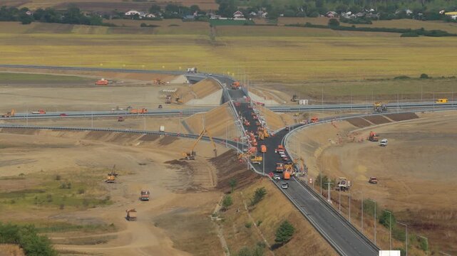 Aerial view of heavy machinery constructing the Autostrada Moldovei A7 highway junction near Bacau, showcasing modern infrastructure development under bright sunlight. 4K video.