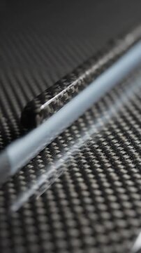Carbon Fiber Texture with White Accents Slowly Rotating in a Seamless Loop. High-Resolution 4k Footage for Design and Technology.