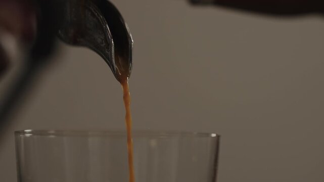 Slow motion closeup shot of espresso poured into glass with professional coffee machine